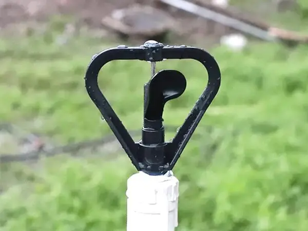 A butterfly sprinkler is inserted into the ground.