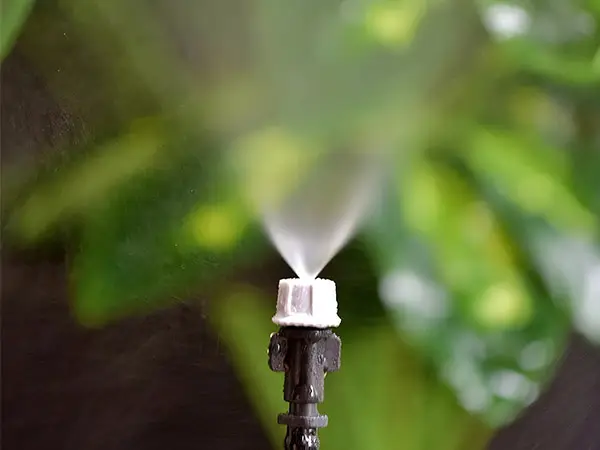 A gray single-head atomizing sprinkler is spraying water.