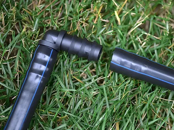 An irrigation elbow connector connects two pipes.