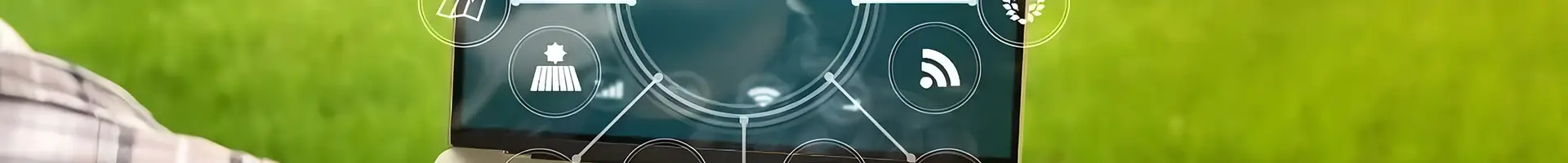 A person is holding a laptop in a field.