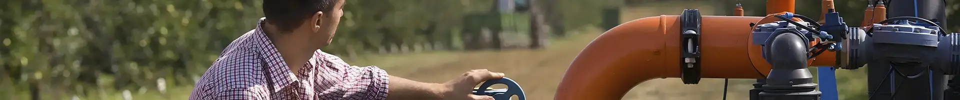 Uma pessoa está agachada no chão e tocando uma tubulação de válvula.