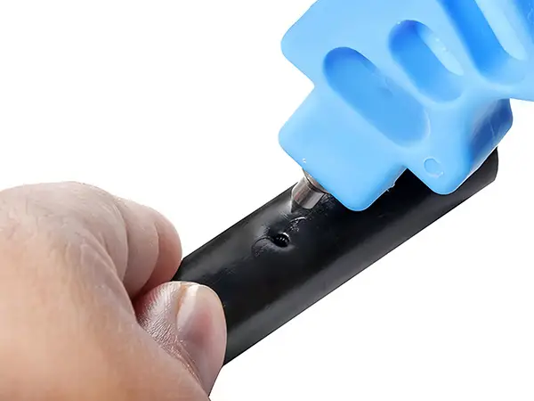 A hand is holding a blue hole punch to punch a pipe.
